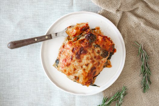 Tasty homemade Italian lasagna served on a rustic setting with rosemary garnish.